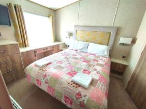 een slaapkamer met een bed met een quilt bij Sand Le Mere Holiday Village Caravan hire in Tunstall