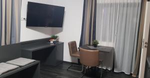 Habitación con escritorio, silla y TV. en APPART-HOTEL, Röntgenstraße, en Herzogenaurach