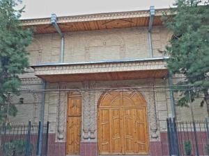 duas portas de madeira num edifício com uma cerca em Hotel KAMILA Prime em Samarkand