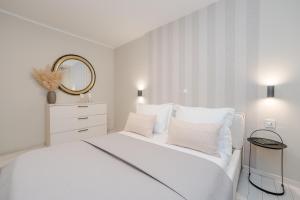 a white bedroom with a white bed and a mirror at Villa Karla in Zadar