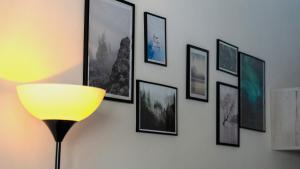 a wall with framed pictures on a wall with a lamp at Magda's garden home. in Galatás