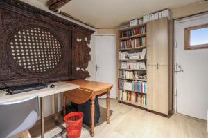 Zimmer mit einem Schreibtisch und einem Bücherregal mit Büchern in der Unterkunft Comfortable 1br in the 11th district of Paris - Welkeys in Paris