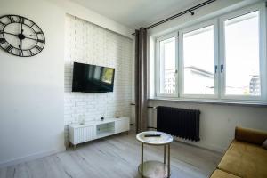 a living room with a clock on a white brick wall at Apartment Marszalkowska Premium Warsaw City Center in Warsaw
