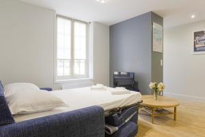 um quarto com uma cama e um sofá azul em Nice flat 300 meters away from the beach - Biarritz - Welkeys em Biarritz