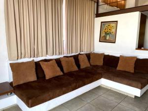 Długa brązowa kanapa w pokoju z zasłonami w obiekcie SUITE MISION JURIQUILLA #1 w mieście Juriquilla