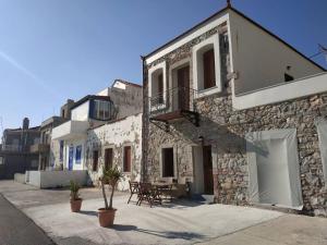 a stone building with a table and a balcony at Seafront two-storey house in Kardamyla in Mármaron