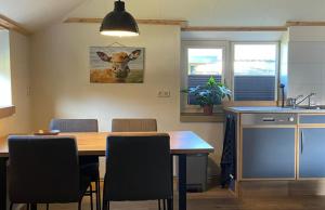 uma cozinha com uma mesa com cadeiras e uma imagem de uma vaca em De Koestal em Odoorn