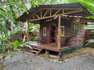 a small wooden cabin with a porch and a bench at Flutterby House Hostel in Uvita
