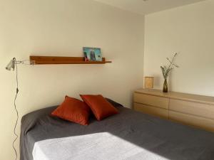 een slaapkamer met een bed met 2 oranje kussens bij Apartamento en Vilanova i la Geltrú in Vilanova i la Geltrú