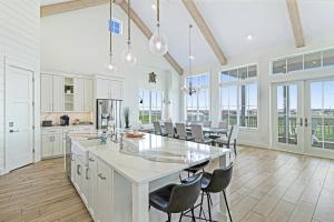 a white kitchen with a large island and chairs at Pelican's Perch at Palmilla Beach in Port Aransas