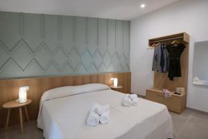 a bedroom with a bed with two white slippers on it at Tarsis Guest House in Baunei