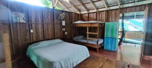 a small room with a bed and a bunk bed at Flutterby House Hostel in Uvita