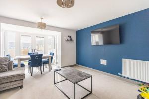 ein Wohnzimmer mit einem Tisch und einer blauen Wand in der Unterkunft Cobbeydale room in Silsden