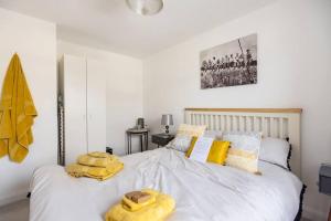 um quarto com uma cama branca e toalhas amarelas em Cobbeydale room em Silsden