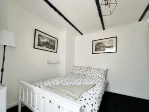 a white bedroom with a crib and two pictures on the wall at Cosy cottage with character. in Brixham