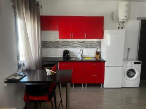 a kitchen with red cabinets and a table and a refrigerator at CASA DOMINGO 3 in La Santa