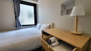 a bedroom with a bed and a table with a lamp at Ueno Woo Hotel in Tokyo