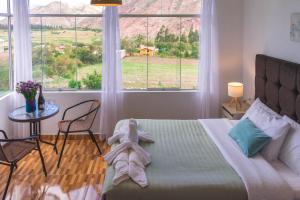 a bedroom with a bed and a table and windows at Casa Yanahuara Valle Sagrado - Urubamba in Urubamba