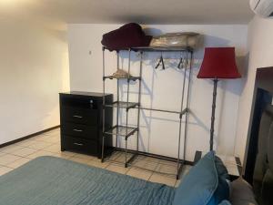 ein Schlafzimmer mit einem Bett, einer Kommode und einer roten Lampe in der Unterkunft Departamento privado con cochera y WIFI alta velocidad in Chihuahua