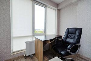 escritorio y silla en una oficina con ventana en Apartament cu vedere la parc, en Chişinău