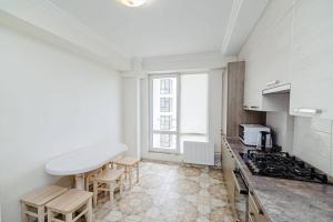 una cocina blanca con encimera y sillas. en Apartament cu vedere la parc, en Chişinău