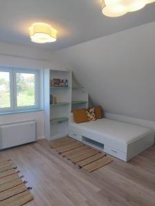 um quarto branco com uma cama e uma estante de livros em ADELINA Apartman 