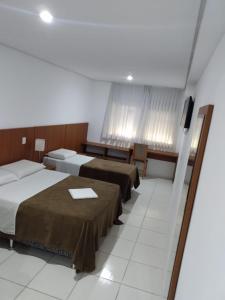 a hotel room with two beds and a television at HOTEL ECONOMICO - 150m Santa Casa, Prox Assembleia e UFRGS in Porto Alegre