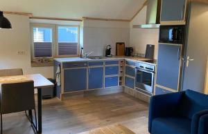 a kitchen with blue cabinets and a table and a blue chair at De Koestal in Odoorn