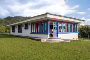ein kleines Gebäude mit blauen Fenstern und einem Grasfeld in der Unterkunft Espectacular casa de montaña in Pereira