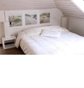 a bedroom with a large white bed with pictures on the wall at Magnifique villa golf du Touquet in Le Touquet-Paris-Plage