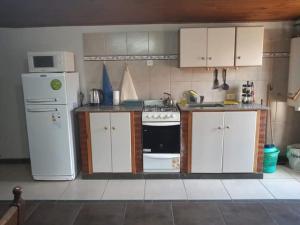 a kitchen with white cabinets and a stove and a refrigerator at Emilia I in Esquel