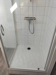 a shower with a glass door and a white tile wall at Au Vélo Fleuri in Bracieux