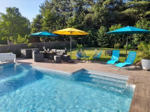 a swimming pool with blue chairs and umbrellas at CHAMBRE DANS UN ECRIN DE VERDURE in Angrie