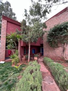 a red brick building with a tree in front of it at Atlas AGUELMAM in Bine el Ouidane +5 photos