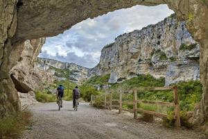 dos personas montando bicicletas por un camino de tierra a través de una cueva en Kataenea. Apartamento en el prepirineo navarro. Naturaleza en Aoiz