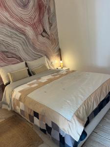 a bedroom with a large bed with a painting on the wall at Atlas AGUELMAM in Bine el Ouidane