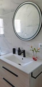 a bathroom sink with a round mirror above it at Kataenea. Apartamento en el prepirineo navarro. Naturaleza in Aoiz