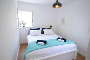 a white bedroom with a bed with two pillows on it at Appartement luxueux à Jérusalem - Katamon in Giv‘at Mordekhay