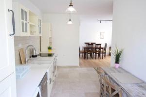 a kitchen with white counters and a wooden table at Appartement luxueux à Jérusalem - Katamon in Giv‘at Mordekhay