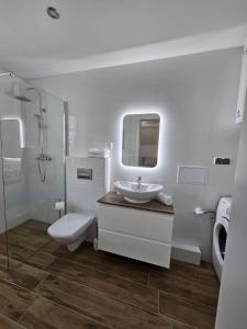 a white bathroom with a sink and a toilet at Apartament w sercu Oliwy in Gdańsk