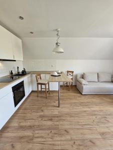 a kitchen and living room with a table and a couch at Apartament w sercu Oliwy in Gdańsk