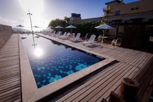 a swimming pool with chairs and umbrellas on a deck at Yak Beach Hotel Natal in Natal