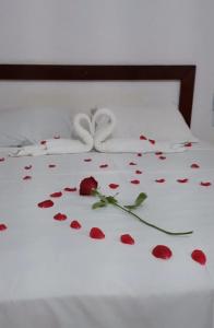 Vila Chale في باورو: سرير مع بتلات ورد حمراء عليه