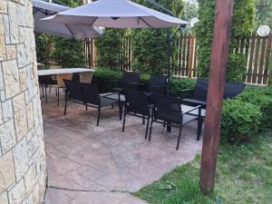 un patio con tavoli, sedie e ombrellone di Pensiunea Constanta a Predeal