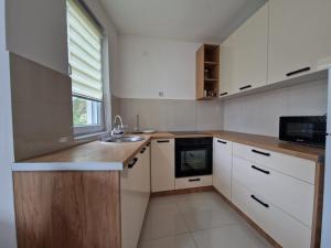 a kitchen with white cabinets and a sink and a window at N&M Apartment in Pirot