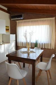 een eettafel met witte stoelen en een raam bij Casa vacanze in famiglia in San Leucio del Sannio