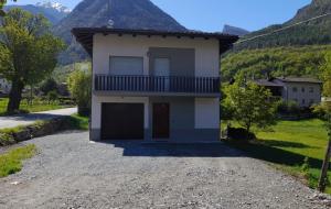 una casa en un camino de grava con montañas en el fondo en Vue du Chateau en Fenis