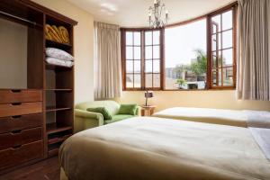 1 dormitorio con 2 camas, silla y ventanas en Peru Star Apart-Hotel, en Lima