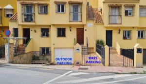 un edificio giallo con un cartello che legge parcheggio esterno di Casa Jardín - residential area -free parking outdoor- Málaga Este a Málaga