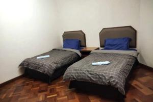 two beds in a room with blue pillows at BC Homestay @ Equatorial Hill Apartment in Brinchang